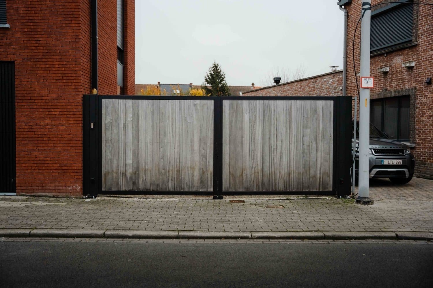 Poort met zwart stalen kader en houten vulling aan de straatkant