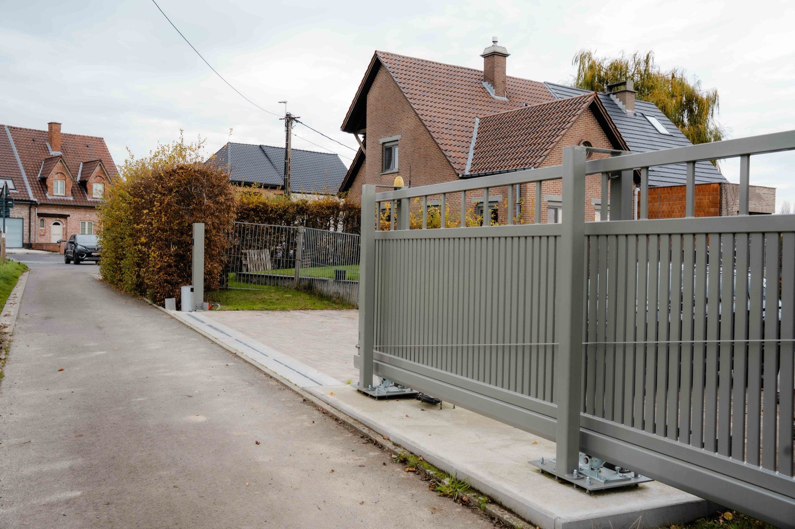 Grijze gemotoriseerde stalen schuifpoort aan een woning in Kerksken