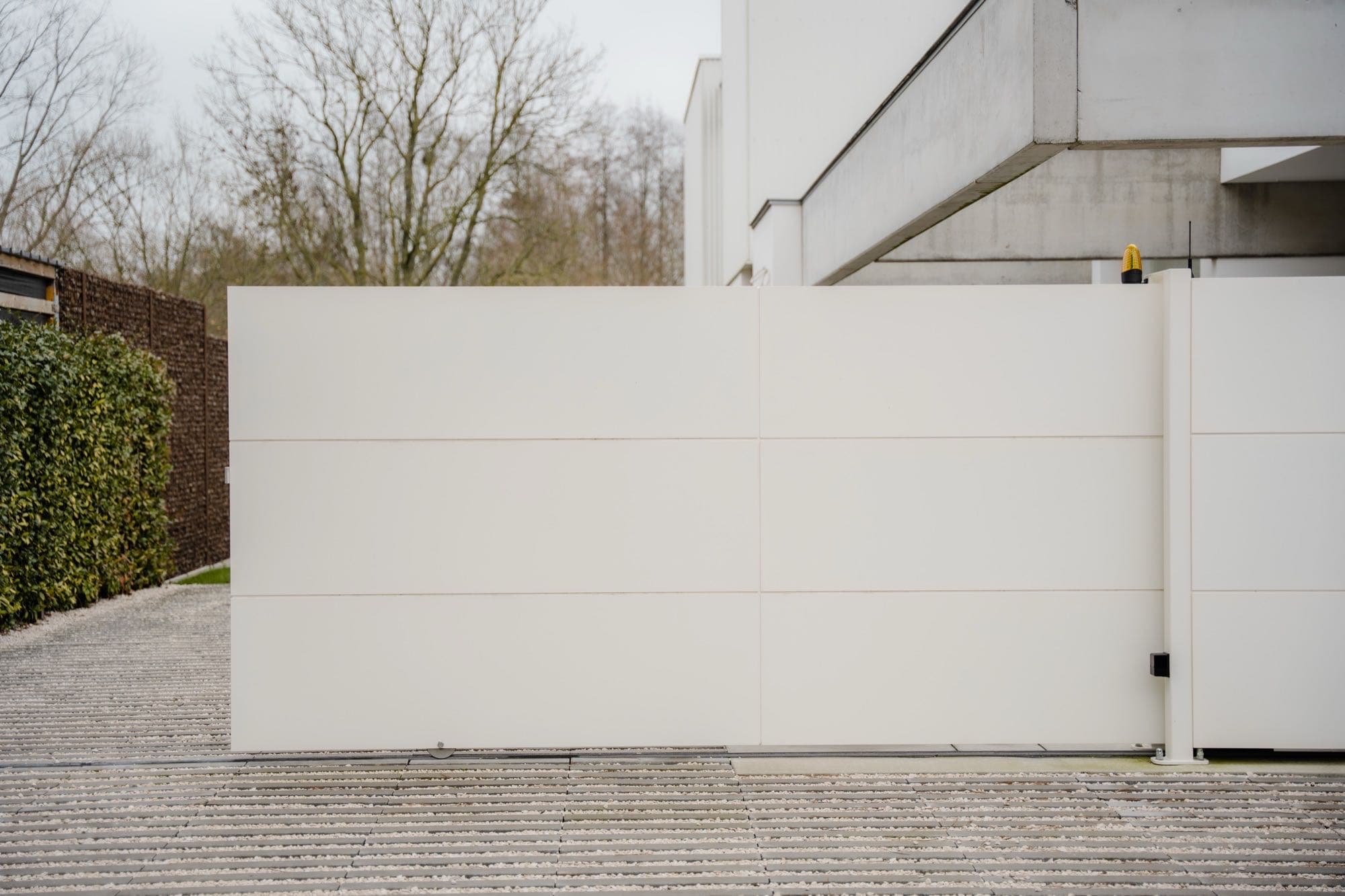 Dichte poort als één wit vlak tussen haag en gevel